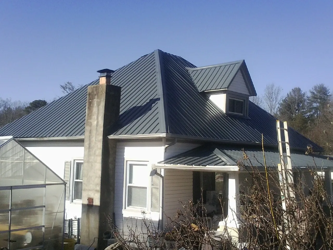 Dark blue standing seam metal roof on a white farmhouse with dormer — Slate & Tile Roof Repair by Roofing Brothers in Botkins