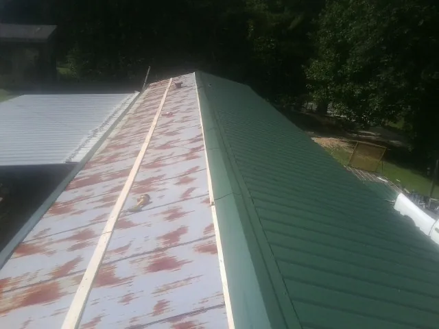 Old rusted panels beside newly installed green metal roofing — Wind Damage Roof Repair by Roofing Brothers in Botkins