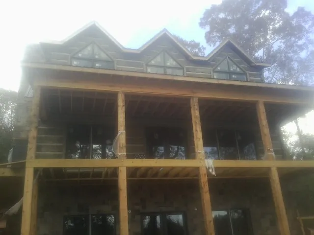 Dormers and porch framing on a large log home under construction — Roof Coating work by our crew in Botkins
