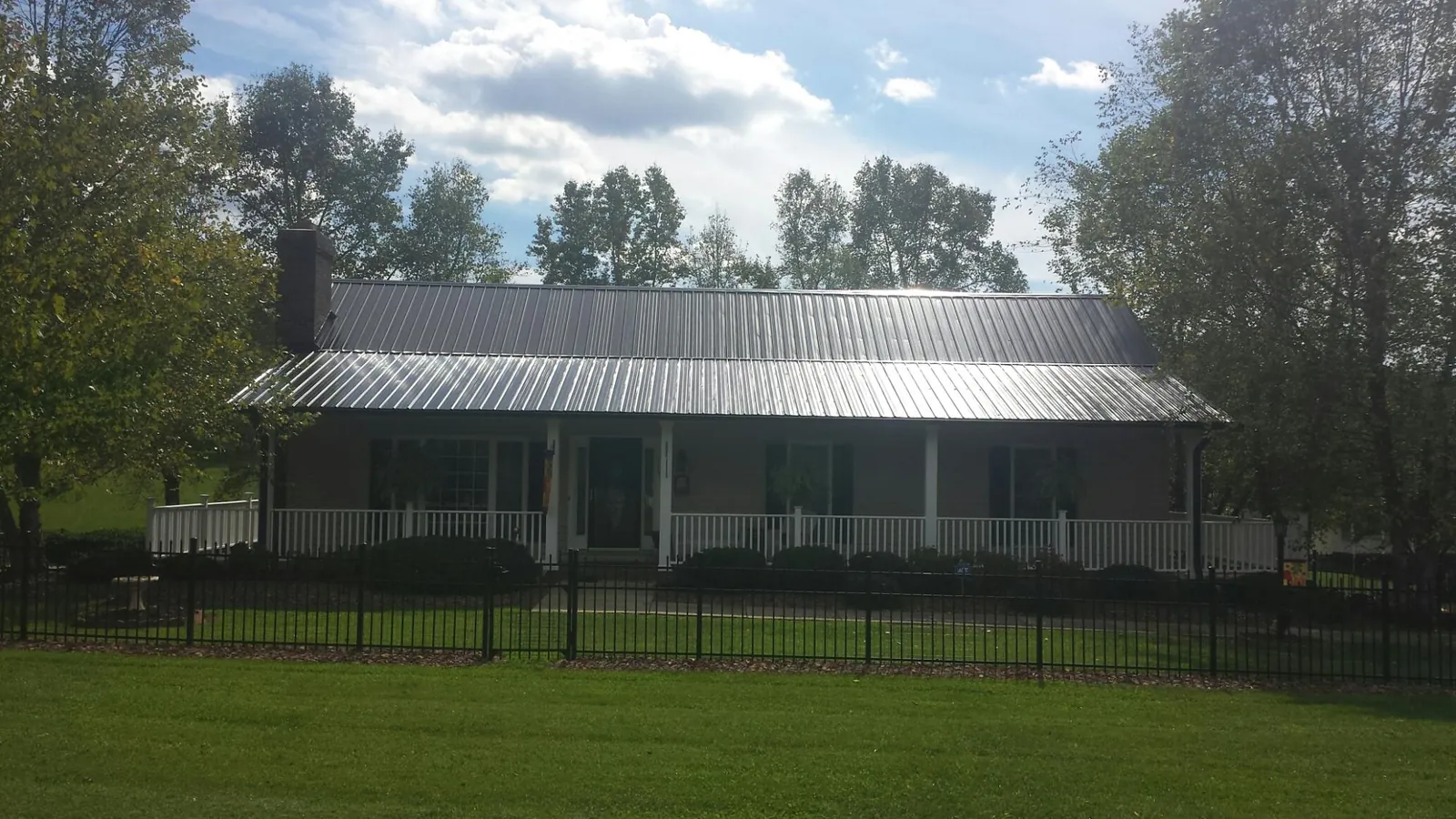 Gray metal roof on a brick ranch with a full width front porch — Gutter Guard Installation work by our crew in Botkins