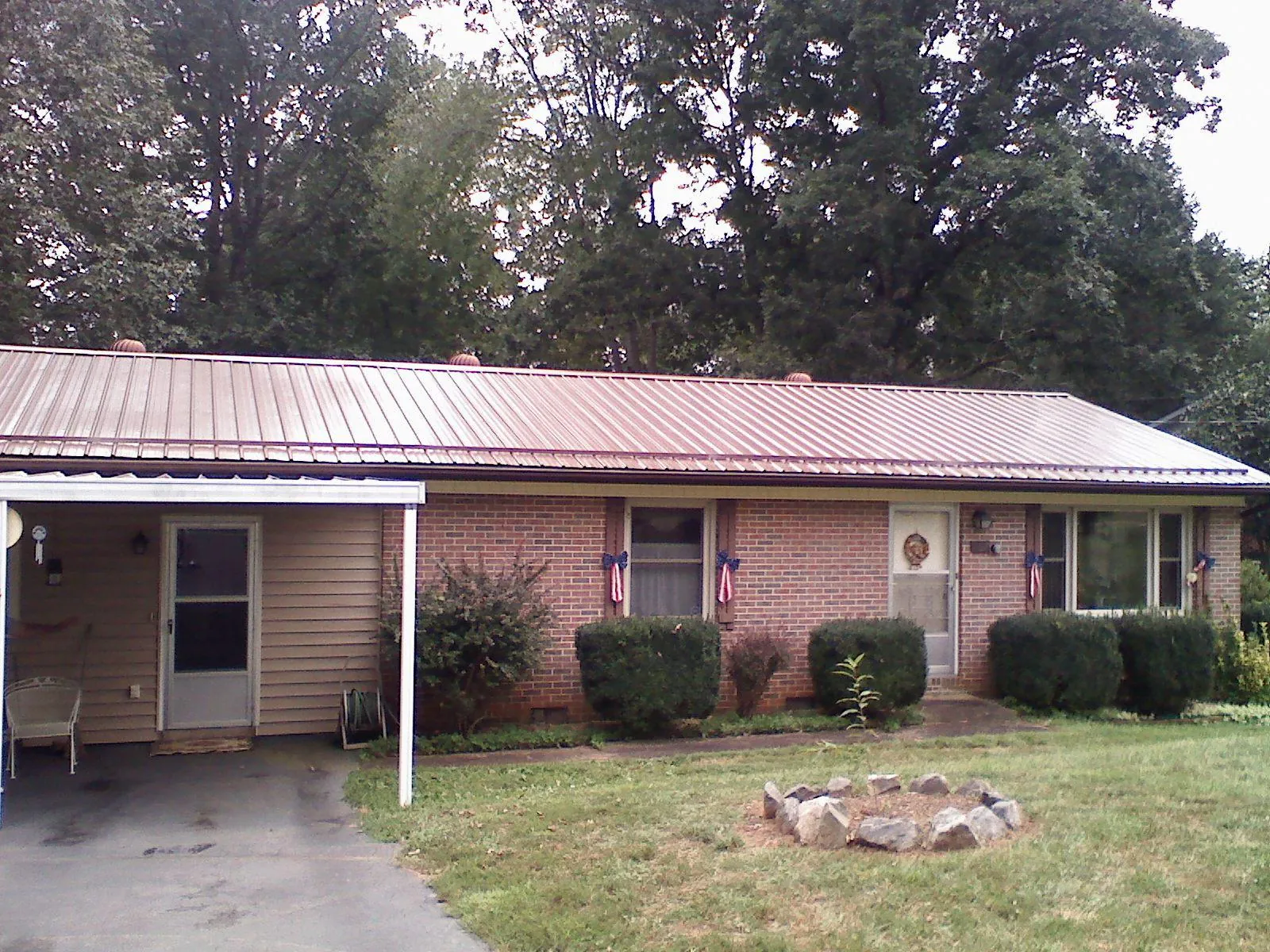Bronze metal roof and carport on a brick ranch home — Roof Repair work by our crew in Botkins