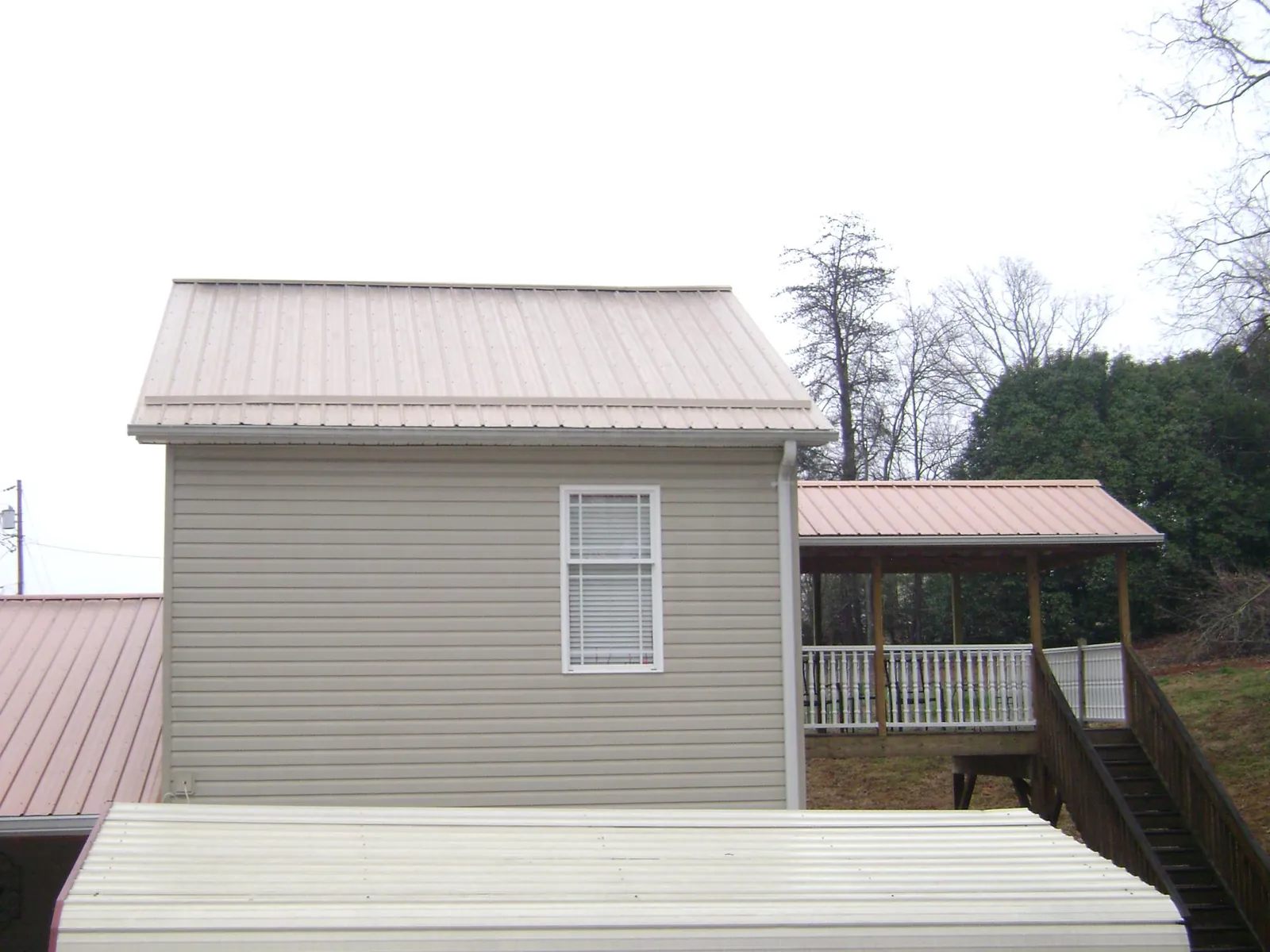 Tan metal roofs on a two story addition and attached porch, from a Roof Replacement job in Botkins