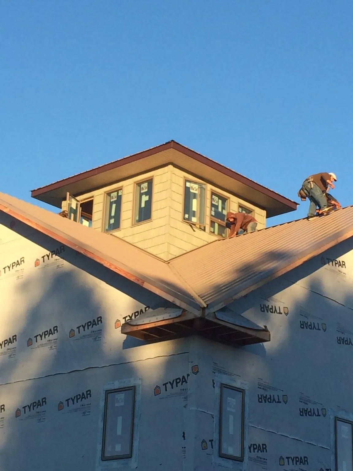 Roofers working around a rooftop cupola on a new metal roof at sunset — Roof Waterproofing in Botkins by Roofing Brothers